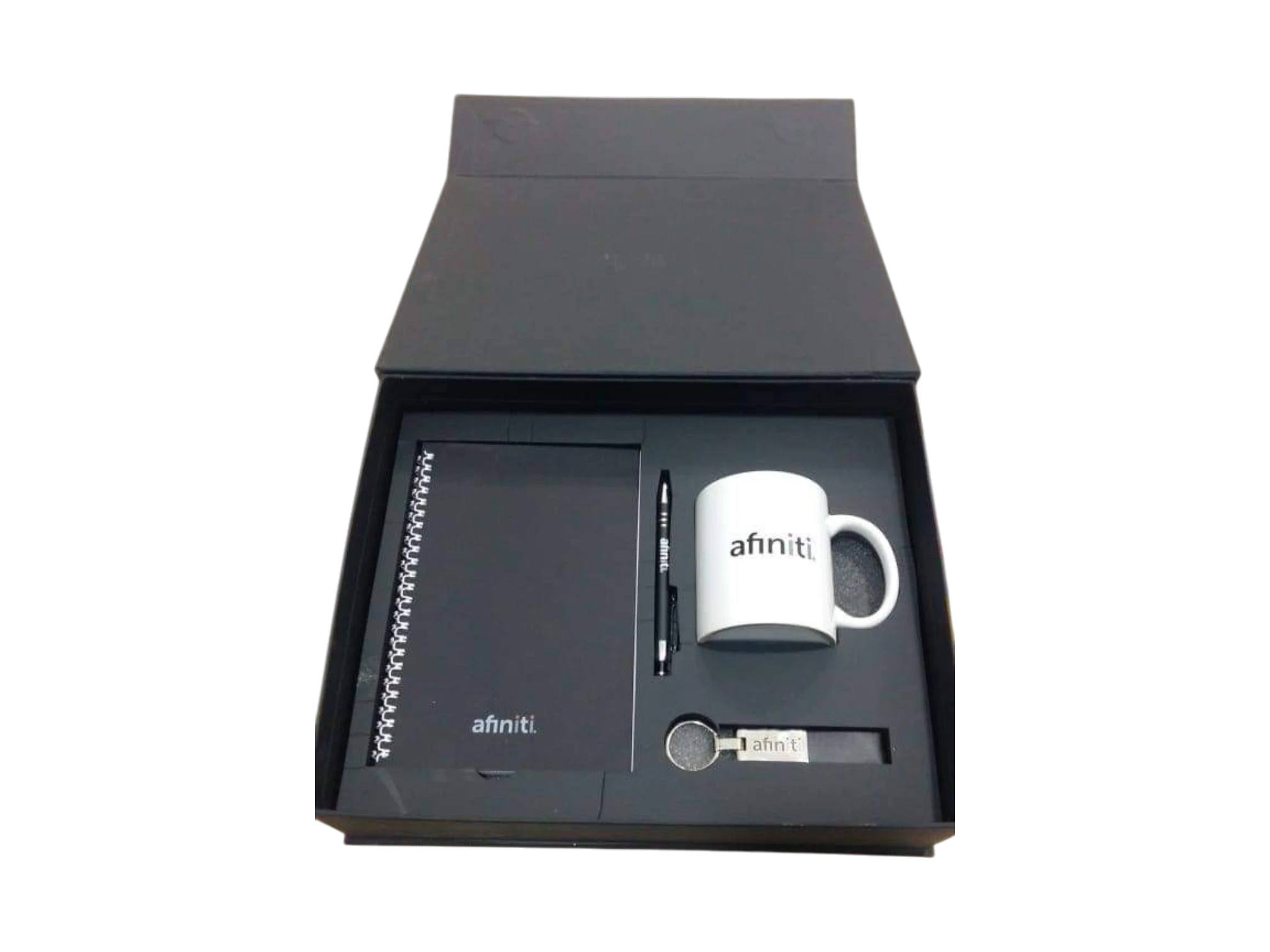 Black and white corporate gift set with spiral notebook, white mug, pen and keychain
